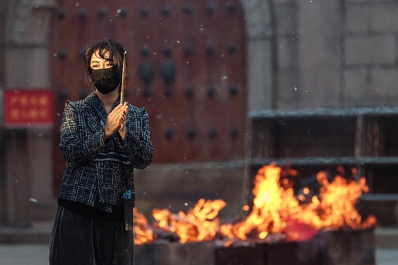 epa10252431 A woman wearing a protective facemask prays in a Buddhist temple, in Shanghai, China, 18 October 2022 (issued 19 October 2022). As China holds its 20th National Congress of the Communist P ...