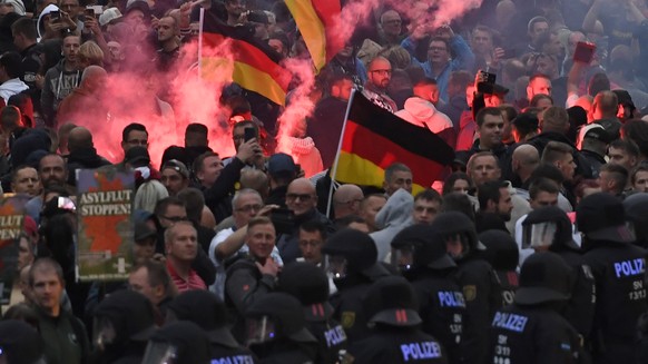 epa06977030 Right wing protesters light flares while facing police as they gather at the place where a man was stabbed in the night of the 25 August 2018, in East German city Chemnitz, Germany, 27 Aug ...
