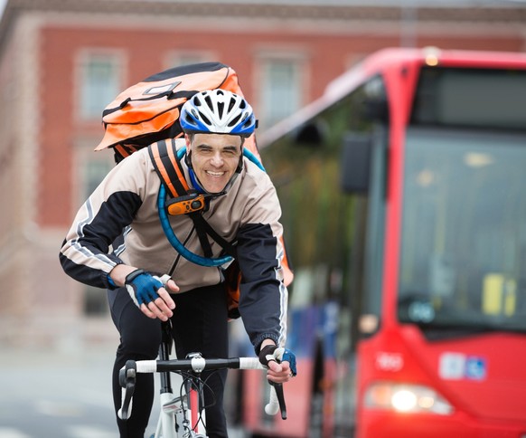 Young male cyclist with courier delivery bag riding bicycle on street