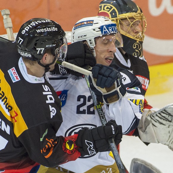 Die Berner Yanik Burren und Torhueter Leonardo Genoni, von links, und der Tessiner Diego Kostner, Mitte, kaempfen um den Puck beim Eishockeyspiel der National League zwischen dem SCB Bern und dem HC A ...