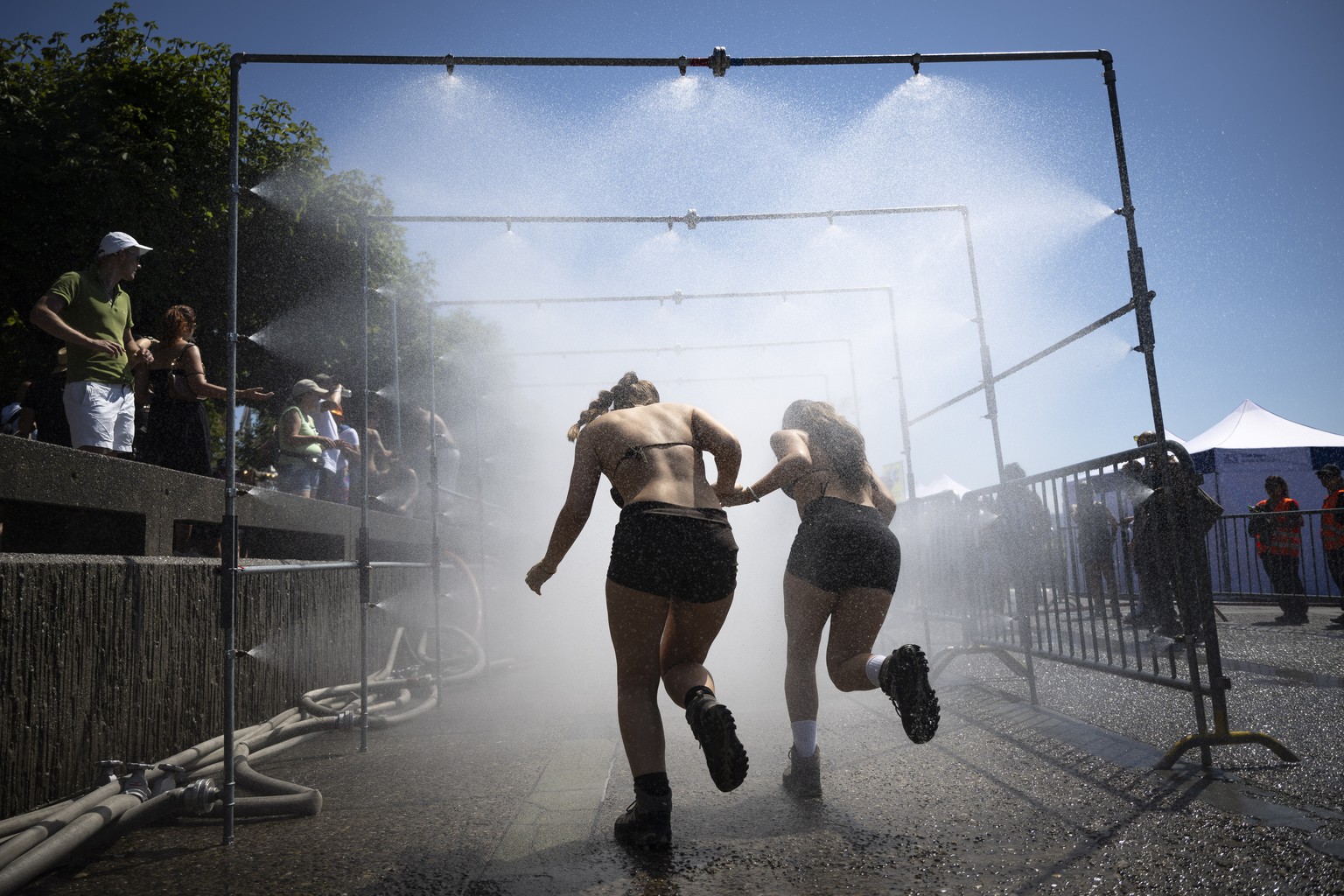 epa13156742 Participants cool off with water spray shower during the 33rd Street Parade in the city center of Zurich, Switzerland, 08 August 2026. The annual dance music event runs this year under the ...