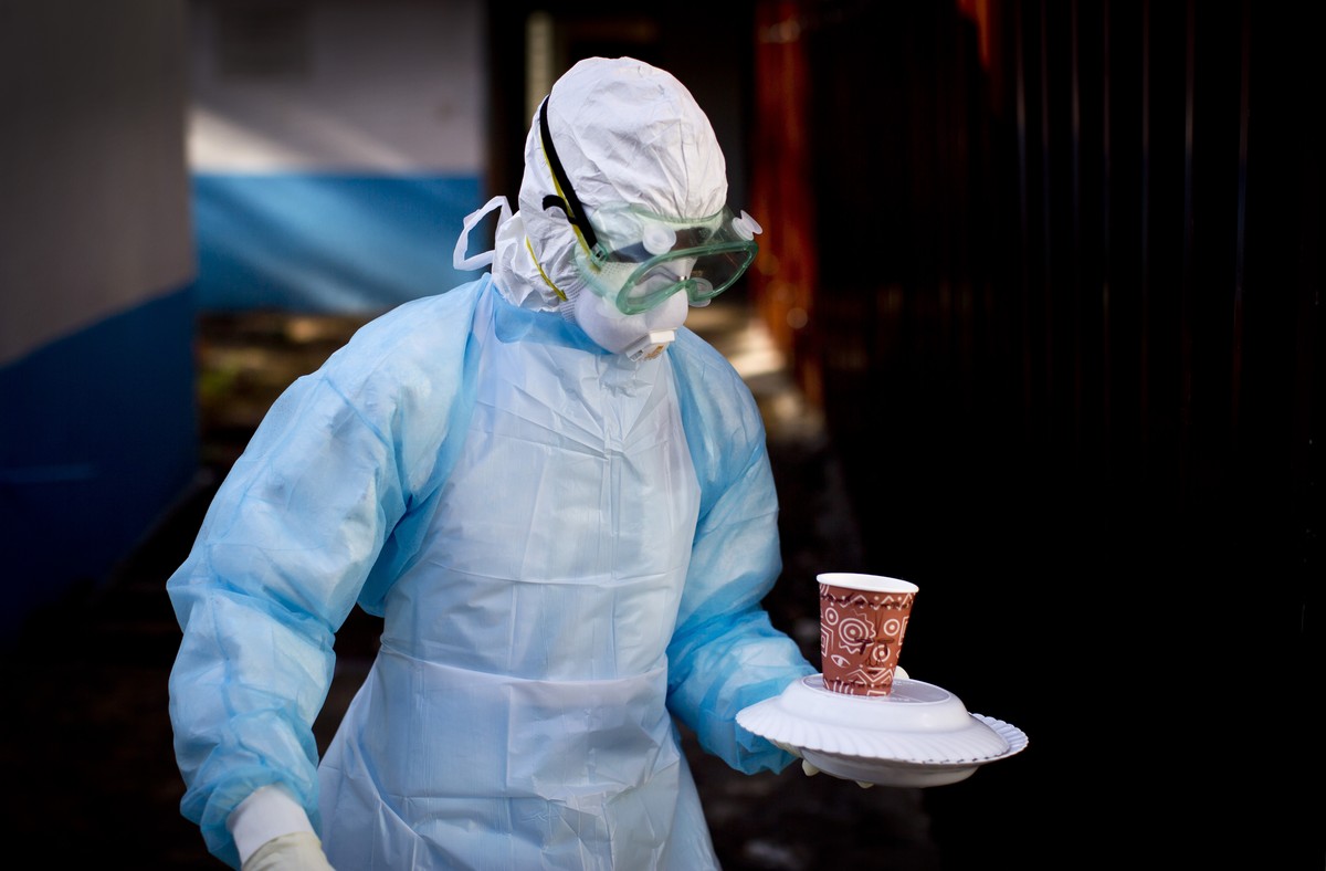 FILE - In this Oct. 8, 2014 photo, a medical worker from the Infection Prevention and Control unit wearing full protective equipment carries a meal to an isolation tent housing a man being quarantined ...