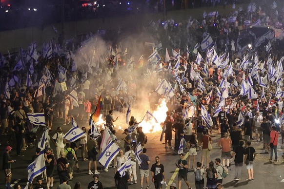 epa10728540 Anti-government protesters with Israeli flags light bonfires as they block the Ayalon highway during a protest against the government's controversial plans to overhaul the justice system…