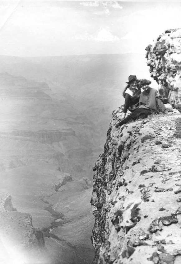 2 YOUNG WOMEN PROBABLY POSED BY ELLSWORTH KOLB ON THE EDGE OF A CLIFF OVERLOOKING INDIAN GARDEN &amp; PLATEAU POINT. FEW TRAILS VISIBLE BELOW. GRCA 30539. CIRCA 1906. KOLB BROS.
