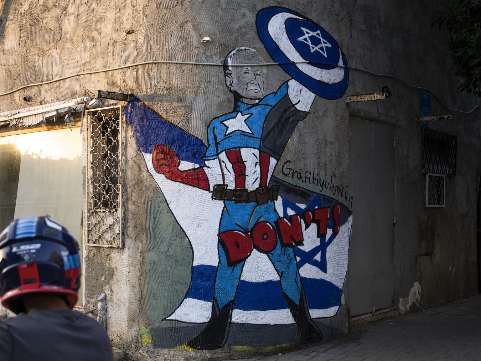 A man cycles next to a newly painted graffiti of Joe Biden, depicting the US president as a superhero defending Israel, Tel Aviv, Israel, Monday, October 8.  August 30, 2023. Biden's popularity in Is...