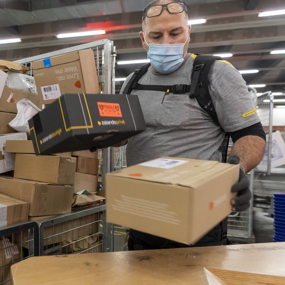 Ein Angestellter traegt ein Exoskelett bei der Sortierung der Pakete im regionalen Paketzentrum der Post in Basel, am Donnerstag, 25. November 2021. (KEYSTONE/Georgios Kefalas)