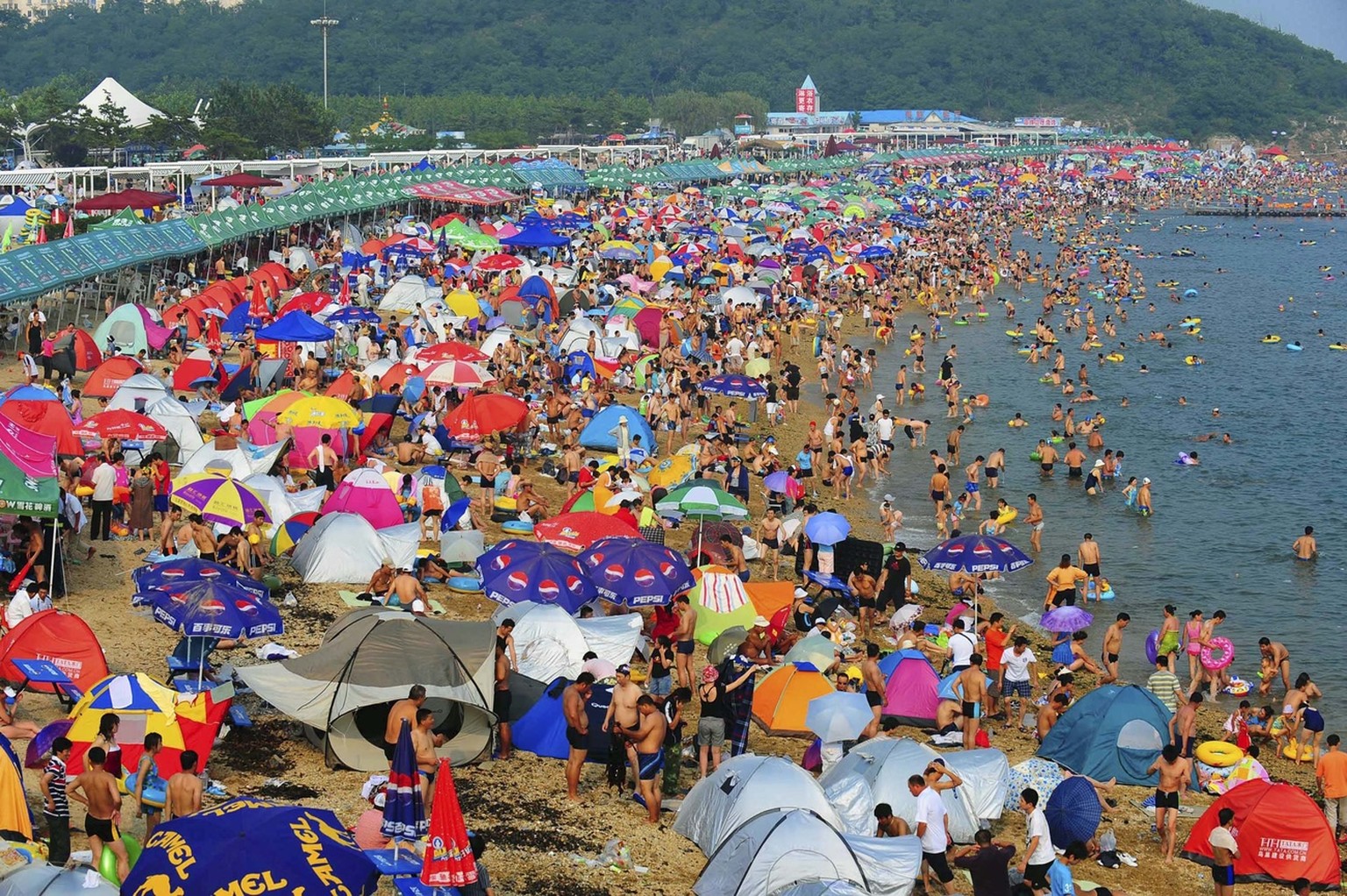 In this photo released by the Xinhua news agency, beach-goers enjoy their summer time at the Fujiazhuang lido, the largest lido in the urban area of Dalian in northeast China's Liaoning province, ...