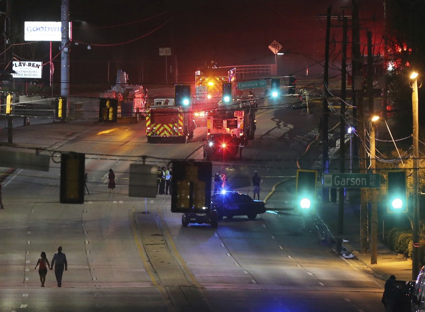 A couple walks away from the scene after a large fire caused an overpass on Interstate 85 to collapse Thursday, March 30, 2017, in Atlanta. Witnesses say troopers told motorists to turn around on the  ...