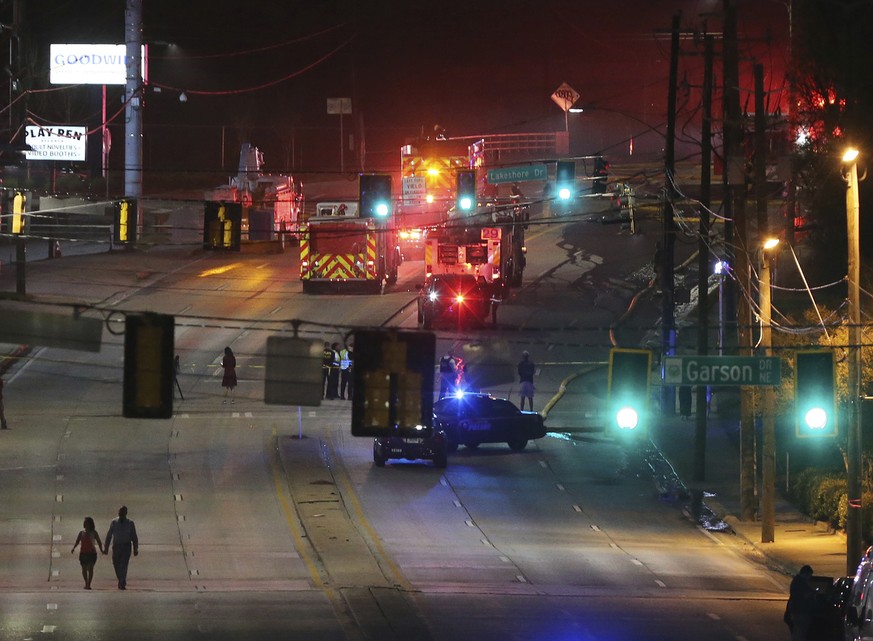 A couple walks away from the scene after a large fire caused an overpass on Interstate 85 to collapse Thursday, March 30, 2017, in Atlanta. Witnesses say troopers told motorists to turn around on the  ...