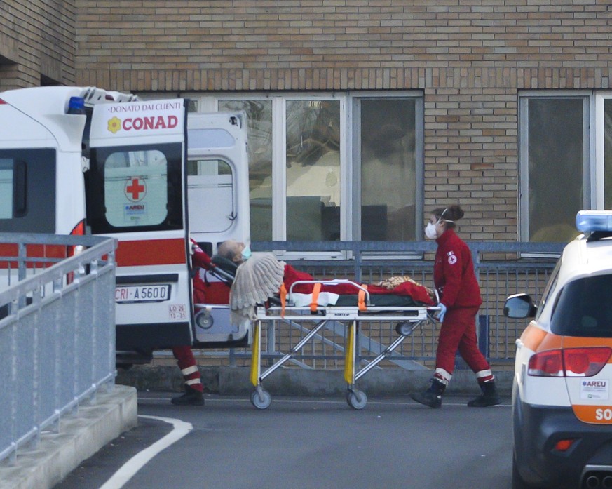 epaselect epa08234042 An elderly person on a stretcher is taken to an ambulance by members of the Italian Red Cross wearing face masks, outside the Codogno Civic Hospital in Lodi, northern Italy, 21 F ...