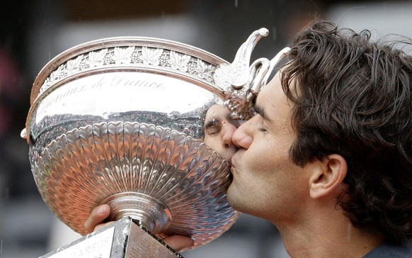 Switzerland's Roger Federer kisses the trophy after defeating Sweden's Robin Soderling during their men's singles final match of the French Open tennis tournament at the Roland Garros s ...