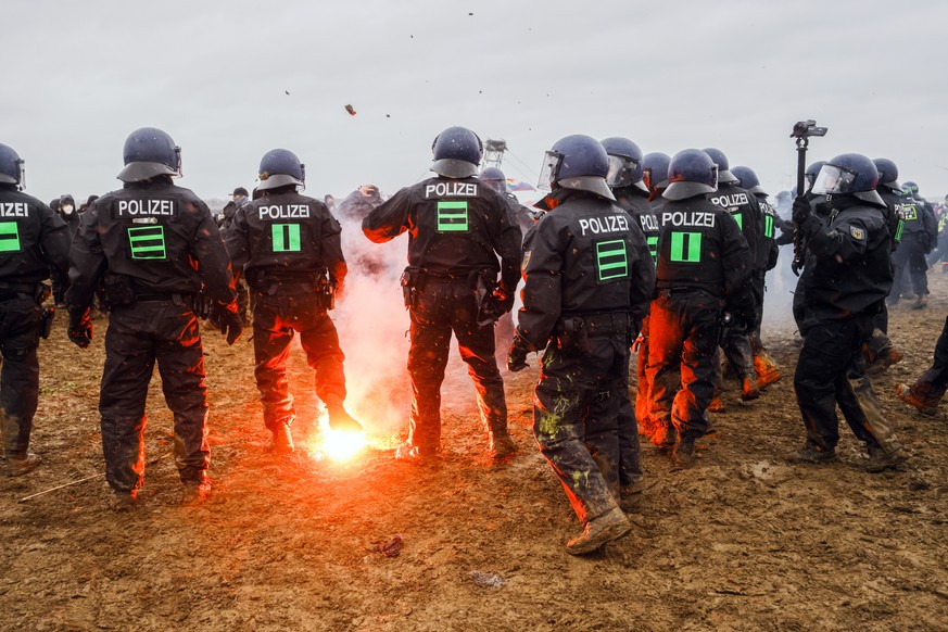 epa10404841 Policemend stand around fireworks during a rally of climate protection activists near the village of Luetzerath, Germany, 14 January 2023. The village of Luetzerath in North Rhine-Westphal ...