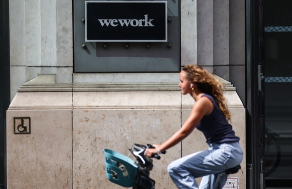 epa10793270 A person rides a bicycle past the entrance to a building belonging to US coworking space company WeWork in Paris, France, 10 August 2023. The workspace-sharing company WeWork on 08 August  ...