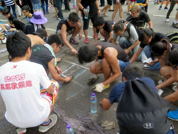 Diese Gruppe Demonstranten entfernt gerade mit Kreide gemalte Schriftzeichen am Boden.