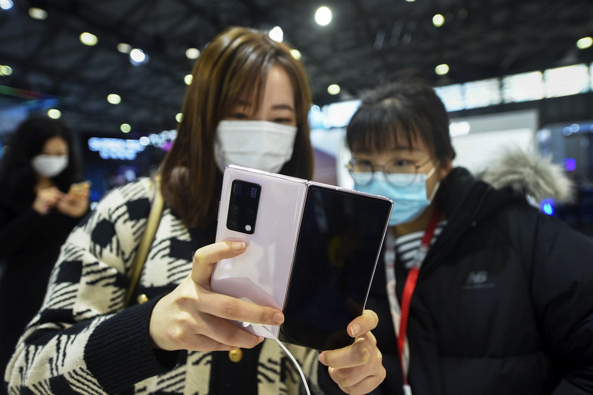 Women wearing face masks to help curb the spread of the coronavirus masks try out the Huawei's latest mobile phone Huawei Mate X2 at the Mobile World Congress in Shanghai, China on Tuesday, Feb.  ...
