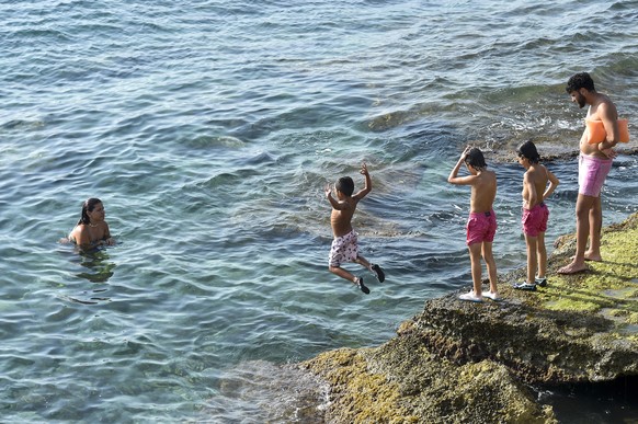 epa10727347 A boy jumps into the sea during the warm and sunny weather in Byblos, Lebanon, 05 July 2023. The temperature is expected to reach 30 degrees Celsius. EPA/WAEL HAMZEH