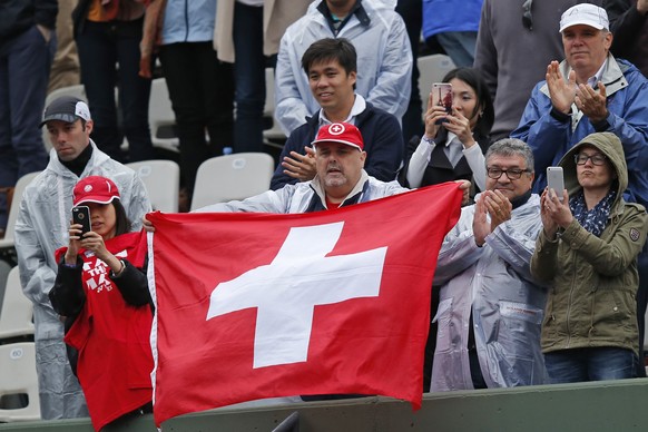 Fans holding the Swiss flag cheer as Switzerland&#039;s Stan Wawrinka wins his fourth round match of the French Open tennis tournament against France&#039;s Gilles Simon in three sets, 6-1, 6-4, 6-2,  ...