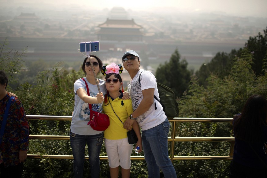 A family takes a selfie from an overlook with a view of the Forbidden City at a park in Beijing, Monday, Oct. 3, 2016. Saturday was China's National Day holiday, the start of a weeklong holiday period ...