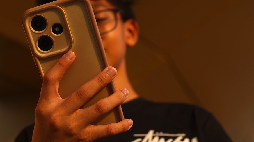 epa13008793 A child looks on his mobile phone in Putrajaya, Malaysia, 01 June 2026. Malaysia's new Child Protection Code (CPC) under the Online Safety Act 2025 (ONSA) takes effect on 01 June for  ...