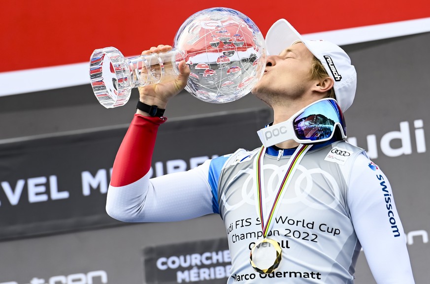 epa09838190 Marco Odermatt of Switzerland celebrates with the men's overall crystal globe trophy on the podium at the FIS Alpine Skiing World Cup finals in Meribel, France, 20 March 2022. EPA/URS FLUE ...