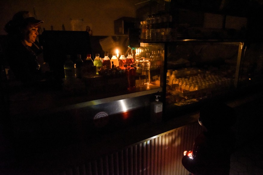 epa10269672 A shop lightened with candles works during electricity shortage in Kyiv, Ukraine, 27 October 2022. Scheduled power cuts were introduced all over the country, including capital Kyiv, power  ...