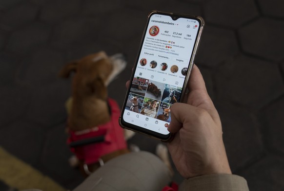 Lt. Tatiana Gaiao calls up the caramelobombeiro Instagram profile featuring Caramello, a rescue dog, at the Catete Fire Brigade in Rio de Janeiro, Brazil, Tuesday, April 12, 2022. Caramello&#039;s onl ...
