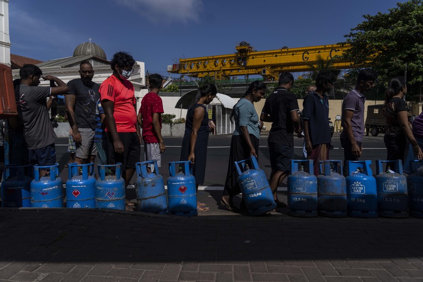 People wait in a queue with empty cylinders to buy domestic gas at a distribution center, in Colombo, Sri Lanka, Tuesday, July 12, 2022. A political vacuum continues in Sri Lanka with opposition leade ...