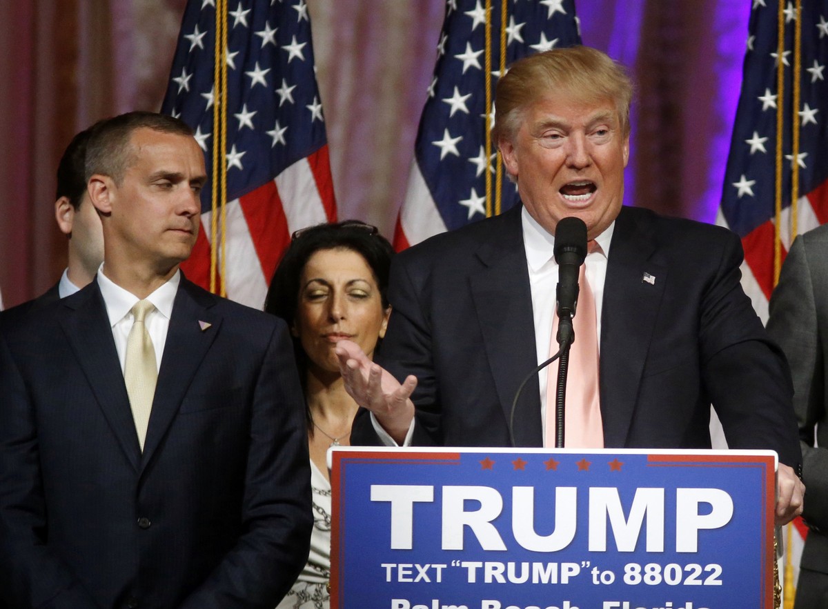 FILE - -In this March 15, 2016 file photo, Donald Trump's campaign manager Corey Lewandowski listens at left are Trump speaks in Palm Beach, Fla. Florida police have charged Lewandowski with simp ...