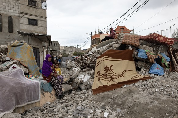 epa11110566 A Palestinian woman and a child stand next to a destroyed house in Rafah, southern Gaza Strip, 28 January 2024. Since 07 October 2023, up to 1.9 million people, or more than 85 percent of  ...