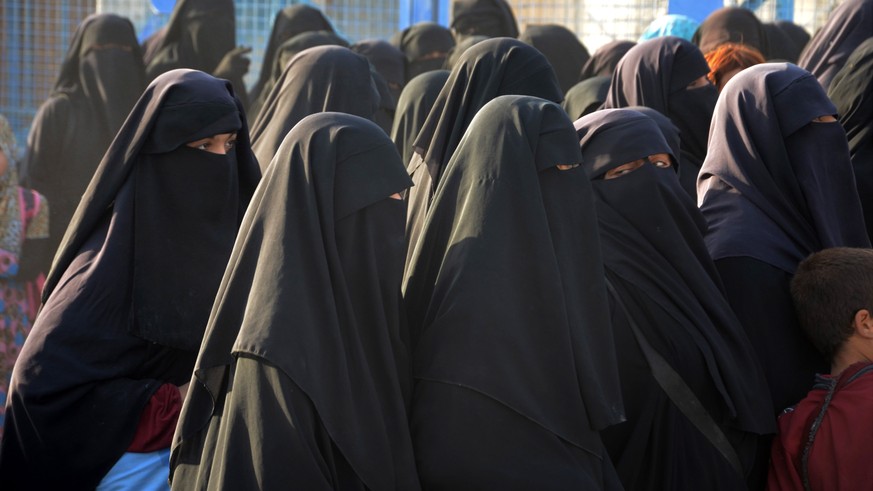 epa10140356 Wives of Islamic state fighters (IS) stand in queue as fighters of Syria Democratic Forces (SDF) launch a search operation inside the al-Hol camp for refugees in al-Hasakah governorate, no ...