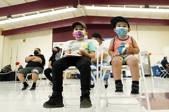 FILE - Oliver Estrada, 5, front left, waits with his brother Adriel, 2, after Estrada received the first dose of the Pfizer COVID-19 vaccine at an Adelante Healthcare community vaccine clinic at Joseph Zito Elementary School, Nov. 6, 2021, in Phoenix. Health systems have released little data on the racial breakdown of youth vaccinations, and community leaders fear that Black and Latino kids are falling behind. (AP Photo/Ross D. Franklin, File)