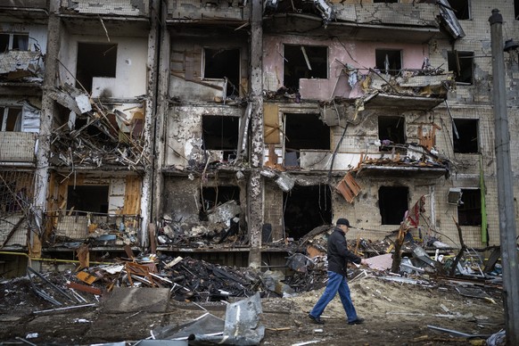 FILE - A man walks past a building damaged following a rocket attack, in Kyiv, Ukraine, Friday, Feb. 25, 2022. The International Criminal Court&#039;s prosecutor has put combatants and their commander ...