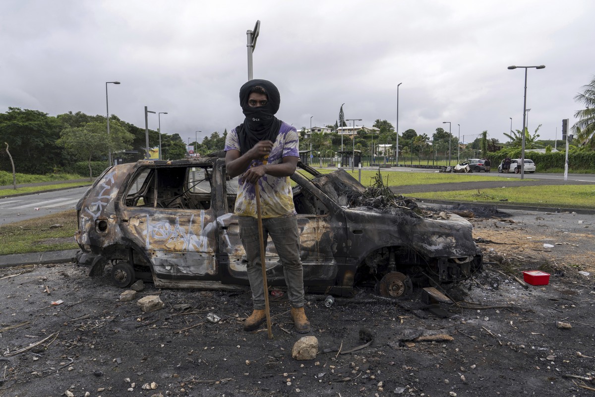A man stands in front a burnt car after unrest in Noumea, New Caledonia, Wednesday May 15, 2024. France has imposed a state of emergency in the French Pacific territory of New Caledonia. The measures  ...