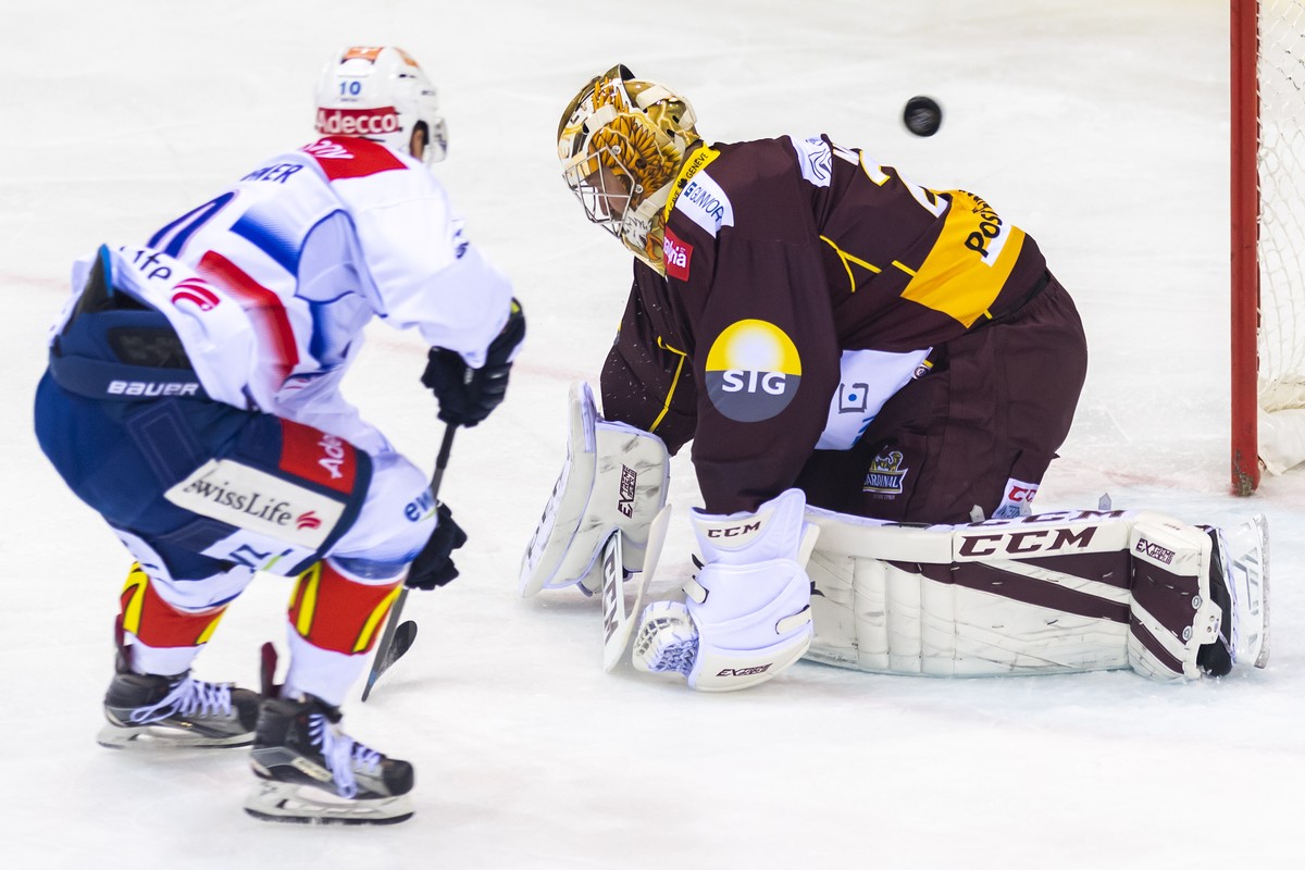Le joueur zurichois, Jerome Bachofner, gauche, a la lutte pour le puck avec le gardien genevois, Robert Mayer, droite, lors du match du championnat suisse de hockey sur glace de National League LNA, e ...