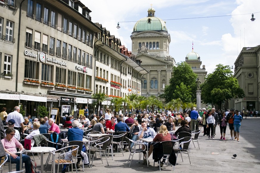 Menschen sitzen in Cafes auf dem Baerenplatz mit dem Bundeshaus im Hintergrund, fotografiert am Sonntag, 5. Juni 2016 in Bern.