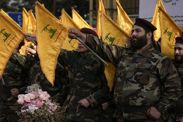 Hezbollah fighters rise their group flags and chant slogans as they attend the funeral procession of their comrade, Mostafa Ahmad Makki, who was killed by an Israeli strike in Syria early Friday, duri ...
