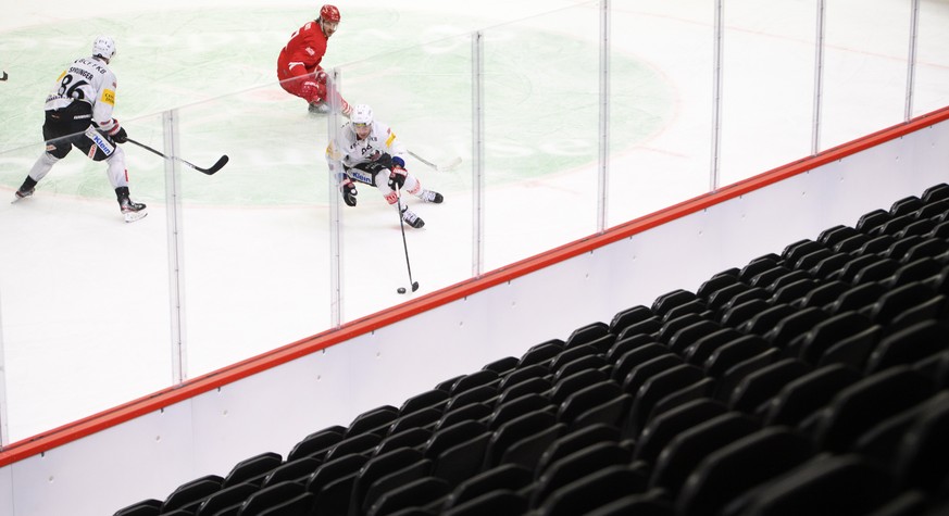 Les joueurs fribourgeois et un joueur lausannois luttent pour le puck devant une tribune vide lors du match a huis clos du championnat suisse de hockey sur glace de National League entre le Lausanne H ...