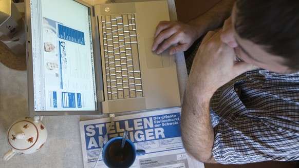 ARCHIV - ZUR GESTIEGENEN ARBEITSLOSENQUOTE STELLEN WIR IHNEN DIESES ARCHIVBILD ZUR VERFUEGUNG - Ein Mann sucht mit seinem Laptop im Internet und im Stellenzeiger des &quot;Tages-Anzeigers&quot; nach e ...