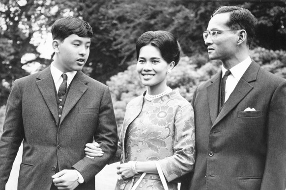 FILE - King Bhumibol of Thailand, right, walks with his wife Queen Sirikit, center, and their 13-year-old son Crown Prince Vajiralongkorn through the gardens of their residence at Sunninghill, Berkshi ...
