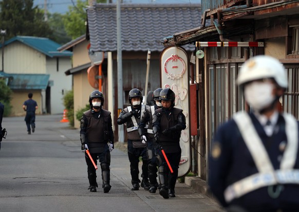 epa10654504 Police officers walk near the scene where an armed man barricaded himself in Nakano, Nagano prefecture, central Japan, early morning 26 May 2023. The police arrested a man suspected of kil ...