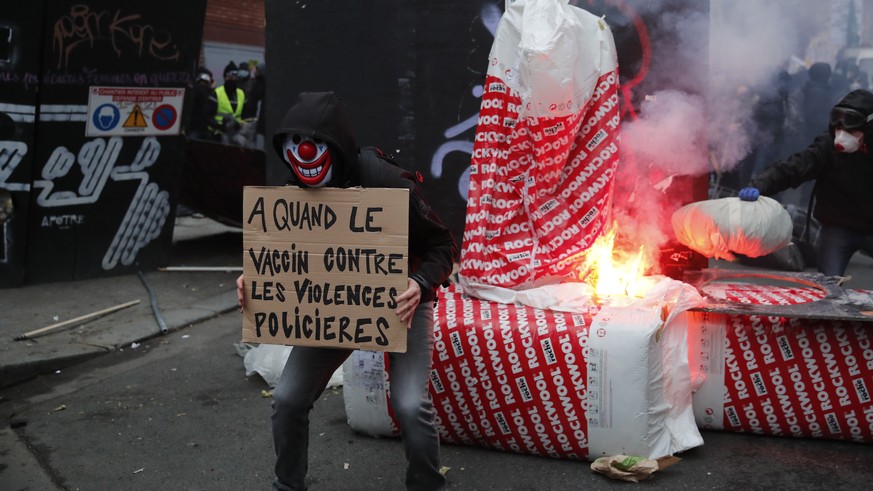 A protester holds a poster reading &quot; When a vaccine against police violence&quot; in front a barricade during a demonstration Saturday, Dec. 5, 2020 in Paris. Thousands marched in protests around ...