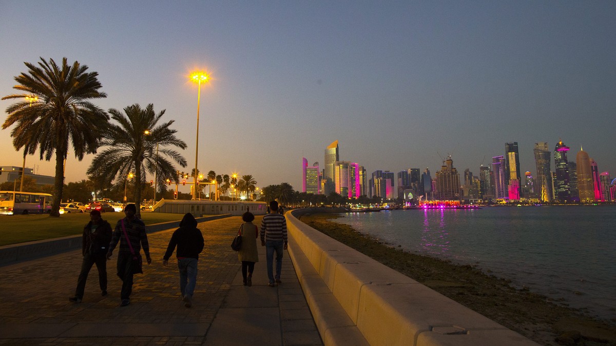 epa04591688 People walk on the corniche promenade in front of the skyline of Doha's West Bay high rise buildings at sunset, Doha, Qatar, 28 January 2015. The men's Handball World Championshi ...