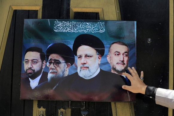 epa11357873 A Houthi supporter touches a placard depicting portraits of late Iranian President Ebrahim Raisi, Iranian Foreign Minister Hossein Amir Abdollahian, and aides, during a visit to the Irania ...