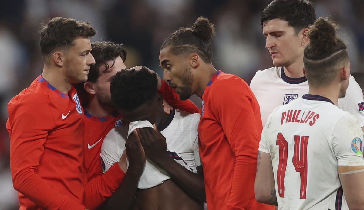 FILE - England players comfort teammate Bukayo Saka after he failed to score a penalty during a penalty shootout after extra time during of the Euro 2020 soccer championship final match between Englan ...