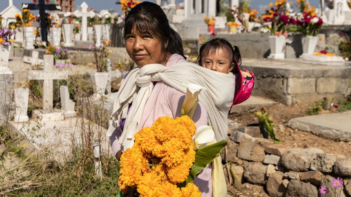SAN PEDRO ARRIBA, TEMOAYA, MEXICO - NOVEMBER 2: Sonia, who is carrying her granddaughter, poses in the cemetery of San Pedro Arriba during 'Day of the Dead' celebrations on November 2, 2022  ...