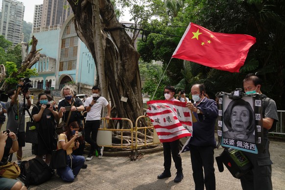 Pro-China supporters hold U.S. flag and a picture of U.S. House Speaker Nancy Pelosi during a protest outside the Consulate General of the United States in Hong Kong, Wednesday, Aug. 3, 2022. U.S. Hou ...