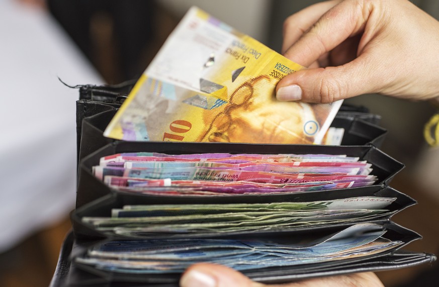 ZUM THEMA GELD STELLEN WIR IHNEN HEUTE, DONNERSTAG, 1. OKTOBER 2015, FOLGENDES NEUES BILDMATERIAL ZUR VERFUEGUNG --- A waitress takes a one ten Swiss franc bill out of a her wallet, photographed in Zu ...