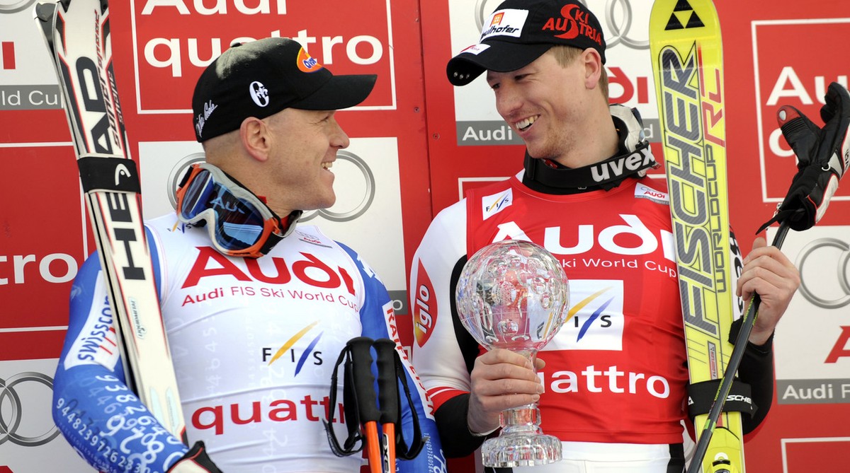 Hannes Reichelt, of Austria, right, looks at Didier Cuche, of Switzerland, as he holds the men's super-G title trophy, at the alpine ski, World Cup finals, in Bormio, Italy, Thursday, March 13, 2 ...