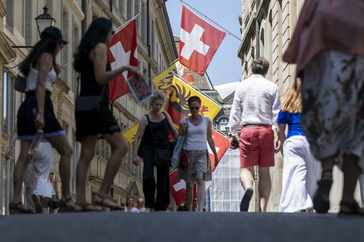 Des personnes se baladent dans la rue de l'hotel de ville en vieille ville de Geneve, pavoiser de drapeaux aux couleurs de Geneve et de la Suisse et de l'union europeenne, ce dimanche 22 jui ...