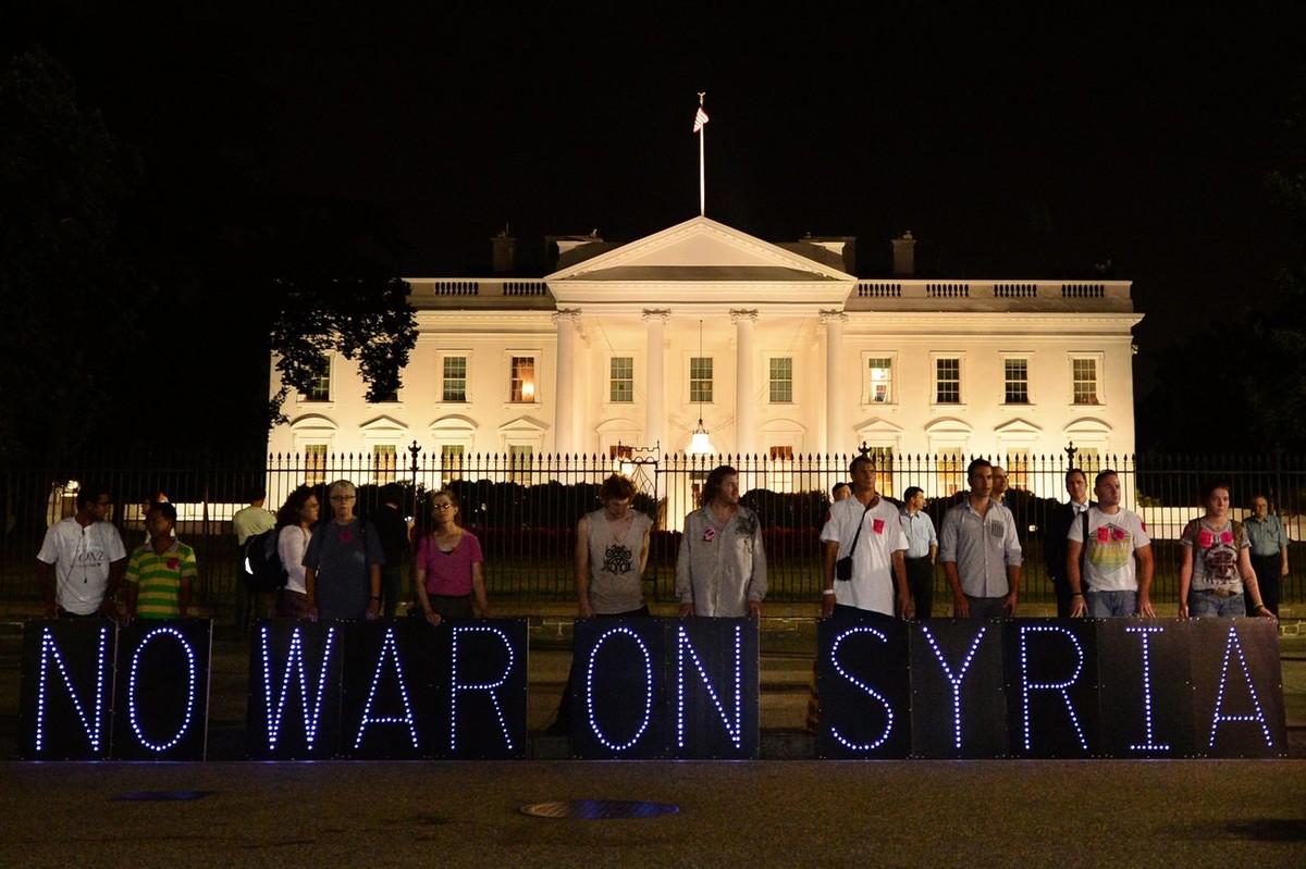 epa03861941 Opponents of a possible military strike on Syria hold a sign that reads 'No War On Syria', as they gathered outside the White House to listen to US President Barack Obama give a  ...